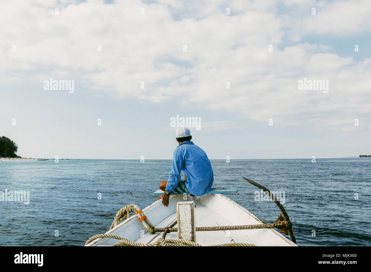 Homme résident local s'asseoir sur le nez du bateau de pêche avec l'ancre et la corde Banque D'Images