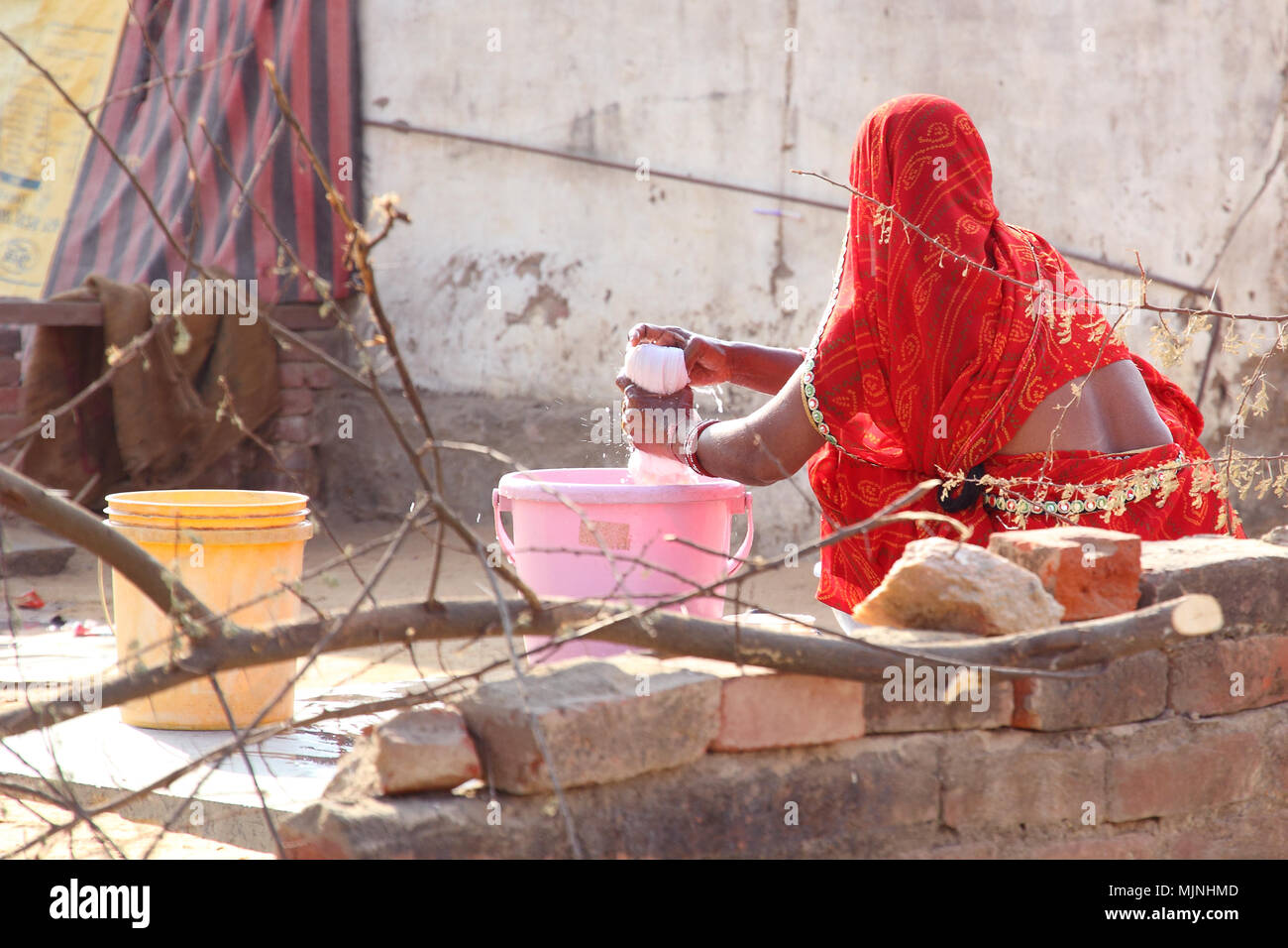 Femme indienne en sari traditionnel belle faire la lessive à la main dans les zones rurales du Rajasthan (Dahmi Kalan région près de Jaipur). Banque D'Images