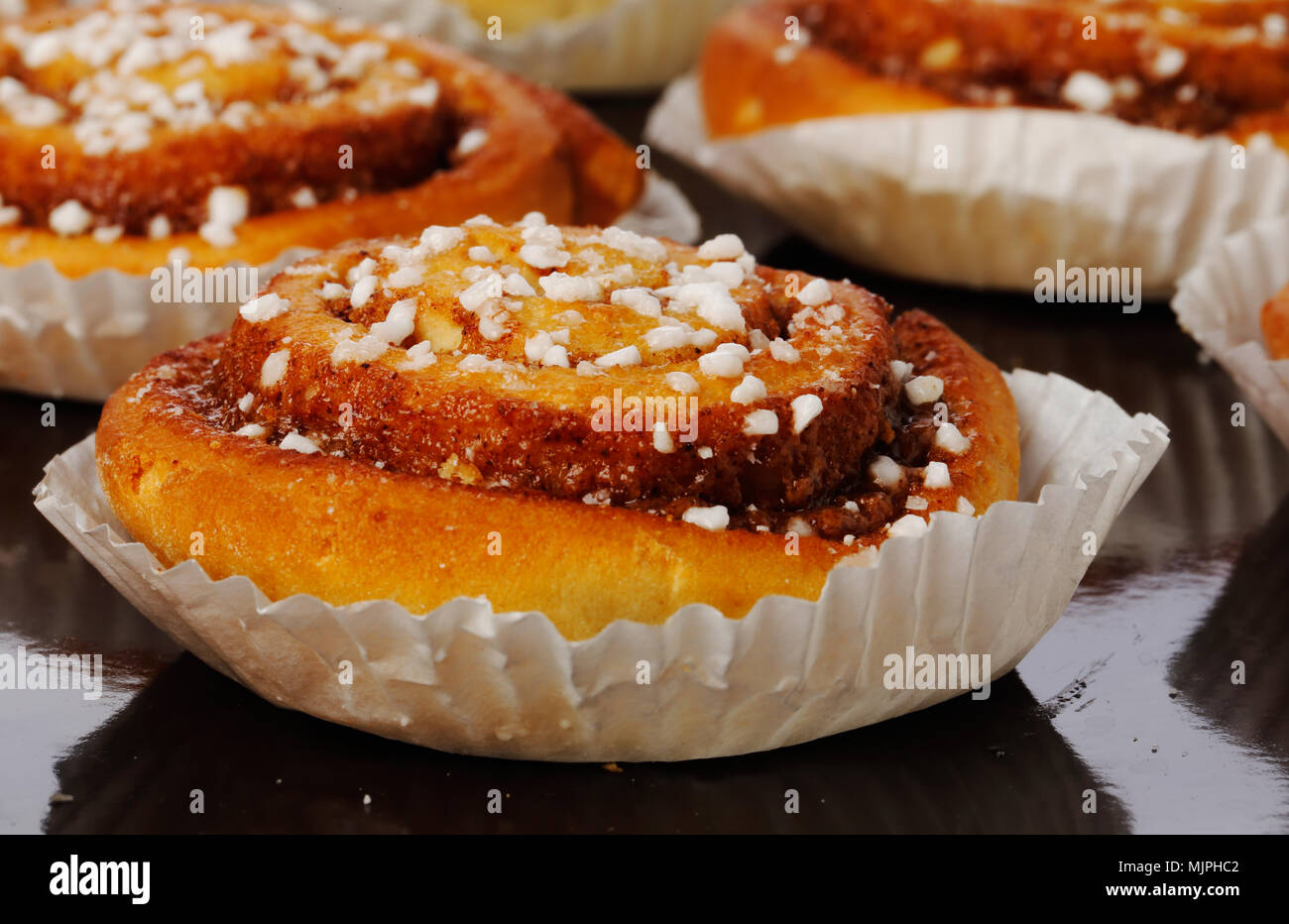 Close-up de brioches à la cannelle dans des boîtes de papier sulfurisé sur une plaque de cuisson. Banque D'Images