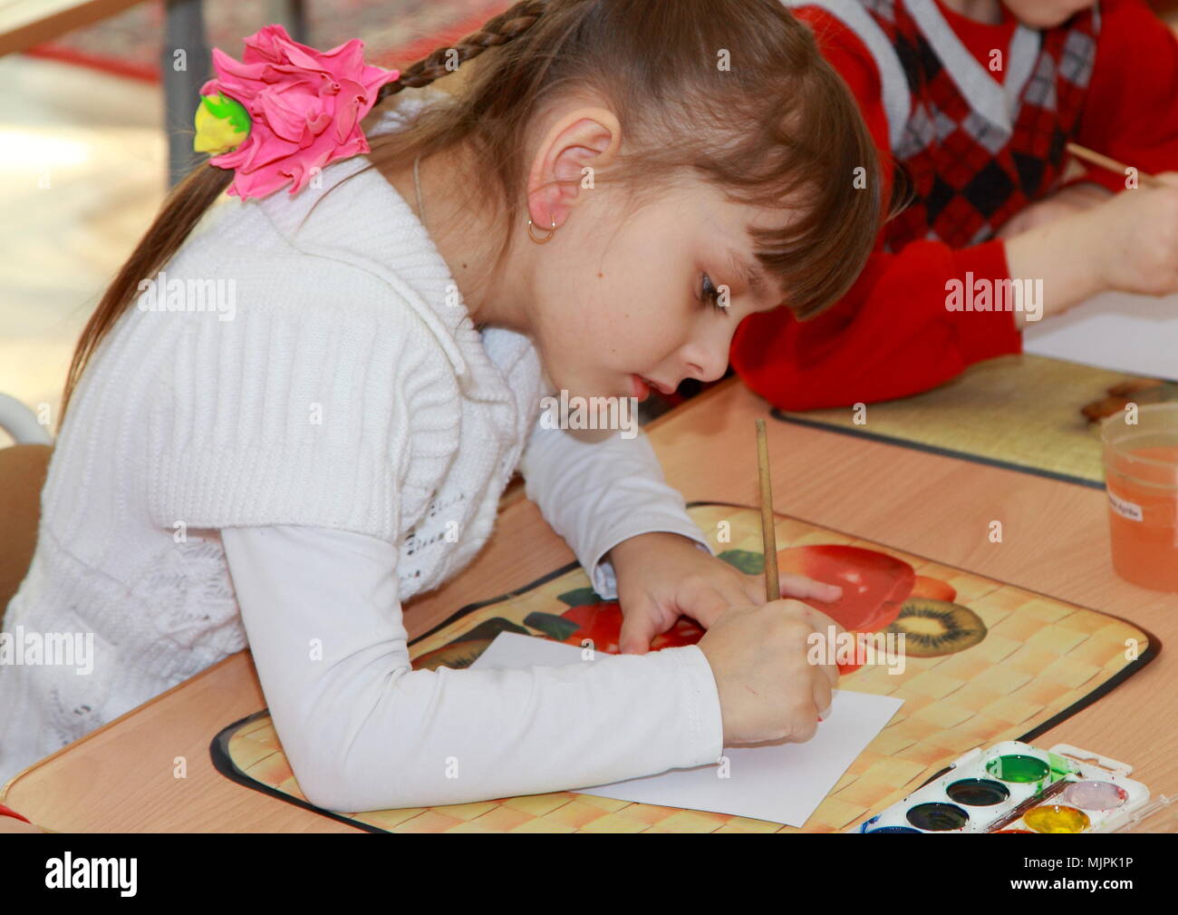 L'enfant s'appuie avec enthousiasme les peintures à la table. Banque D'Images