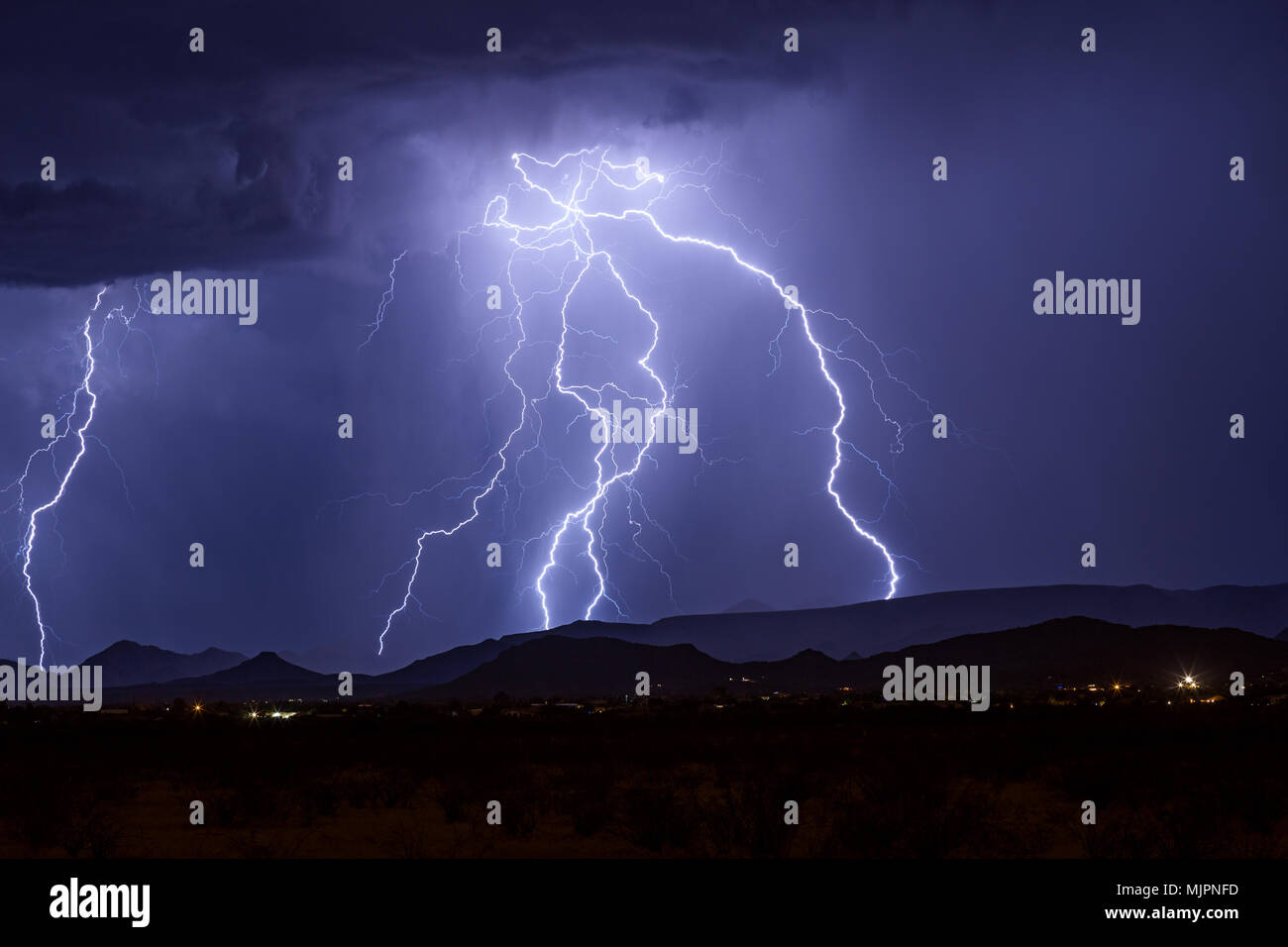 Des éclairs lumineux éclairent le ciel au-dessus de Carefree, en Arizona, alors qu'ils frappent une montagne pendant un orage d'été Banque D'Images