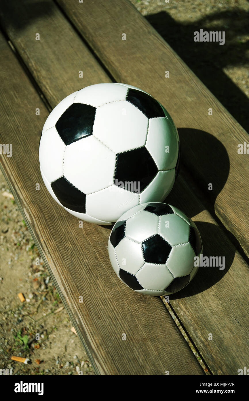 Deux ballons de soccer sur un parkbench au printemps Banque D'Images