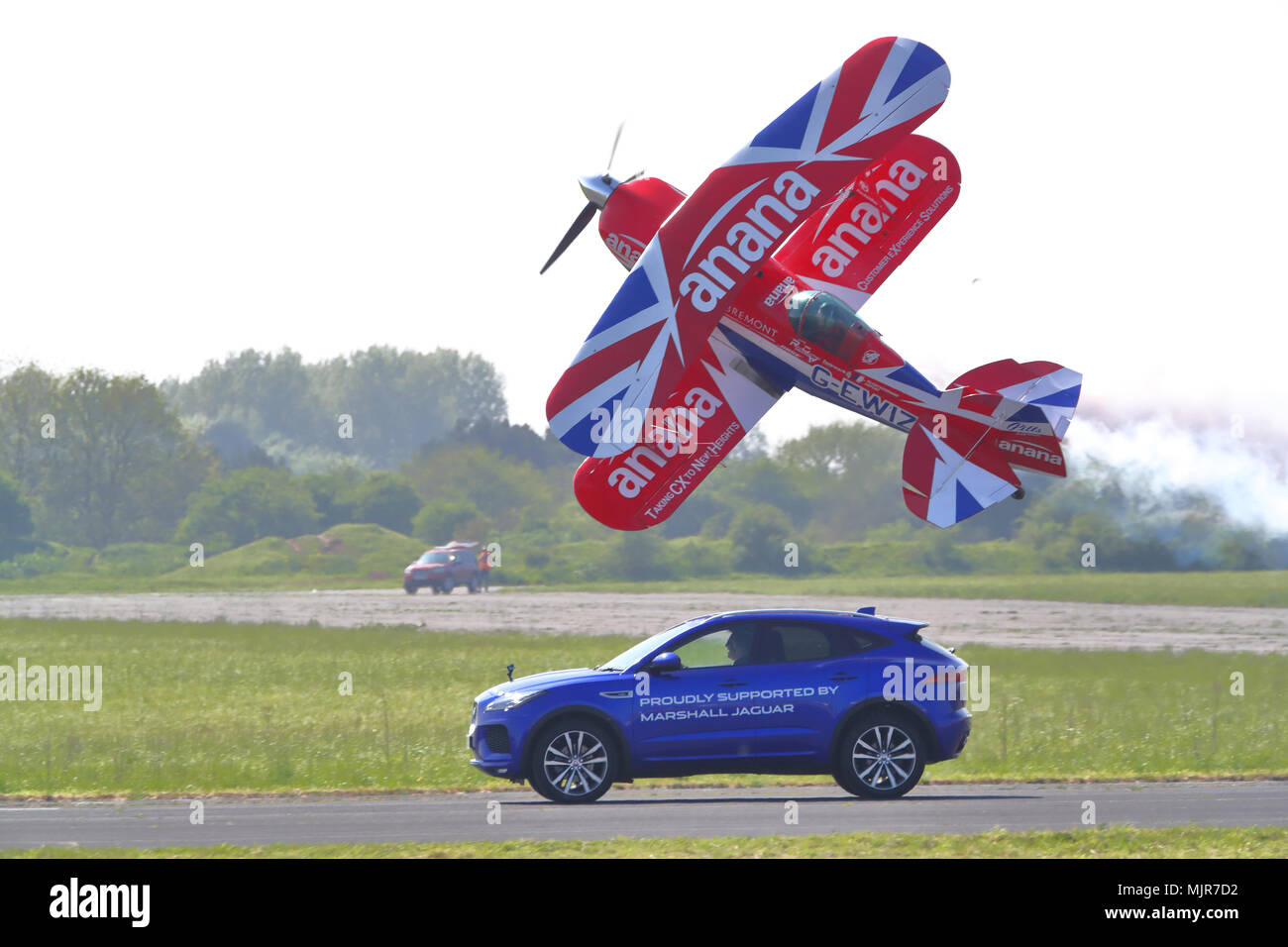 L'Oxfordshire, UK, 6 mai 2018. Le pilote casse-cou Richard Goodwin a volé son biplan Pitts Special, aux côtés d'une Jaguar F-Pace le long de la piste d'Abingdon. C'était la première fois que cette cascade a été montré au Royaume-Uni. Banque D'Images