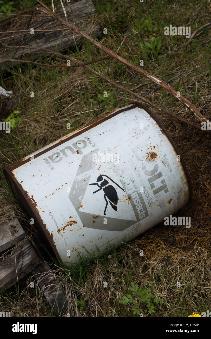Un vide, le baril de métal rouillé de l'insecticide jetés dans l'herbe et les mauvaises herbes. Banque D'Images