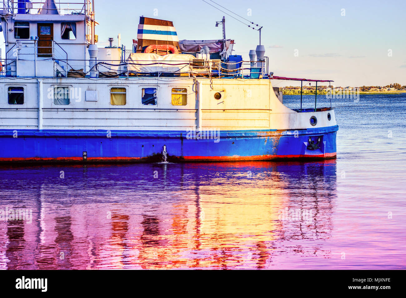 Une croisière navire touristique se reflète dans l'eau à l'aube Banque D'Images