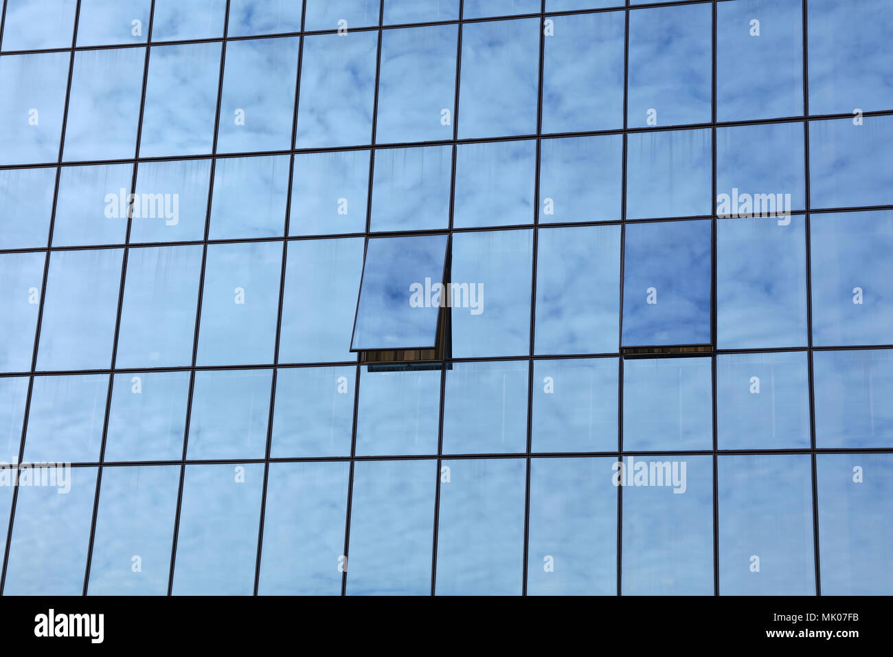 Ciel nuageux Ciel bleu reflet dans verre de bâtiment de bureau avec fenêtres ouvertes, low angle view Banque D'Images