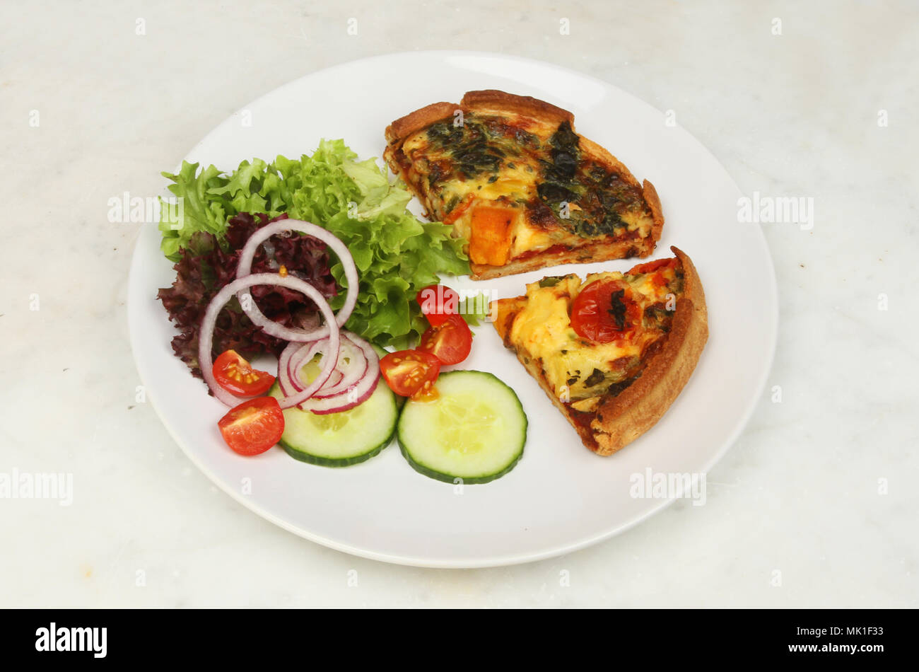 Quiche aux légumes méditerranéens et de la salade sur une assiette avec de la salade sur une table de marbre Banque D'Images