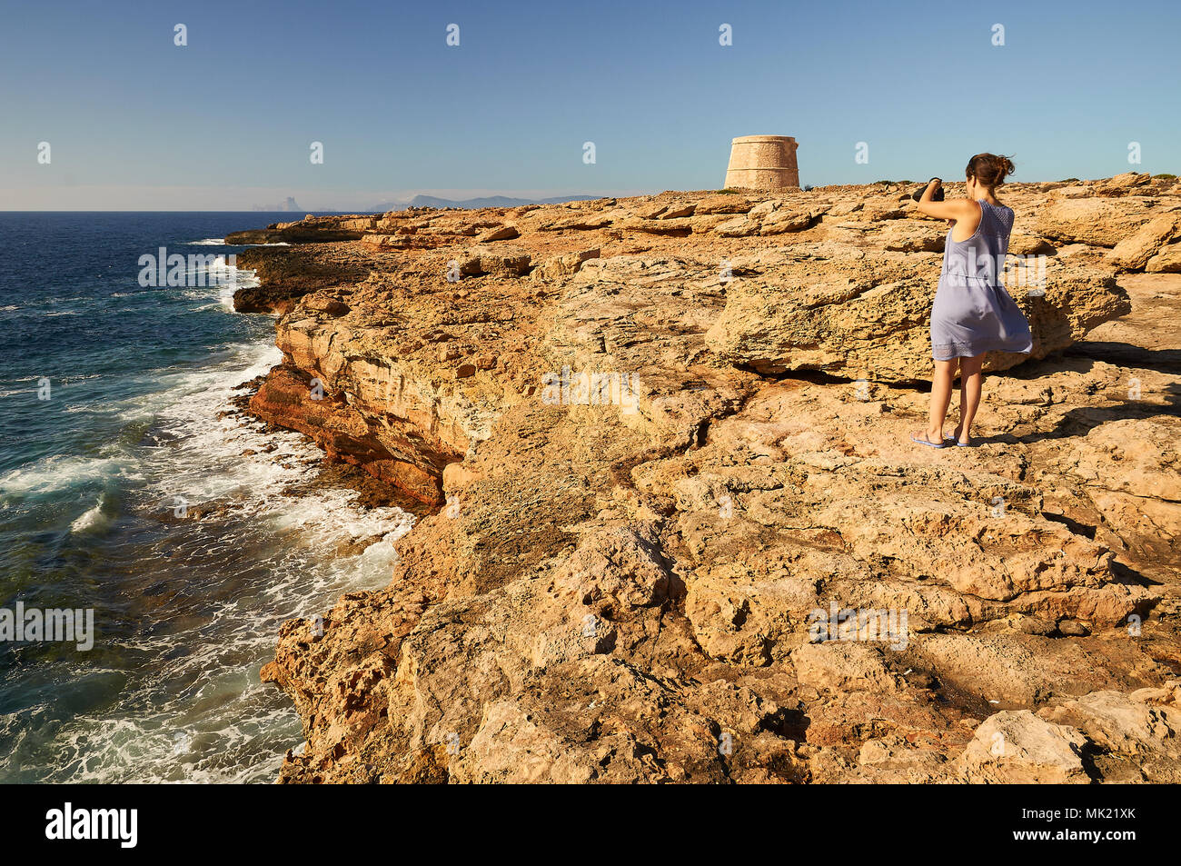 Femme photographiant la côte près de la tour de défense avec Sa Gavina Es Vedrá Island dans la distance à Formentera (Baléares, Espagne) Banque D'Images