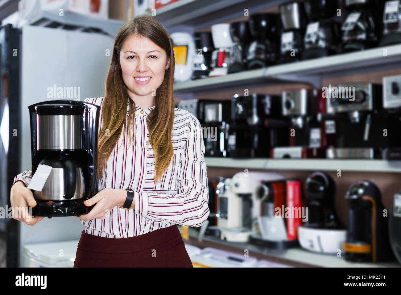 Jeune femme vendeur montrant cafetière dans les appareils domestiques l'article Banque D'Images