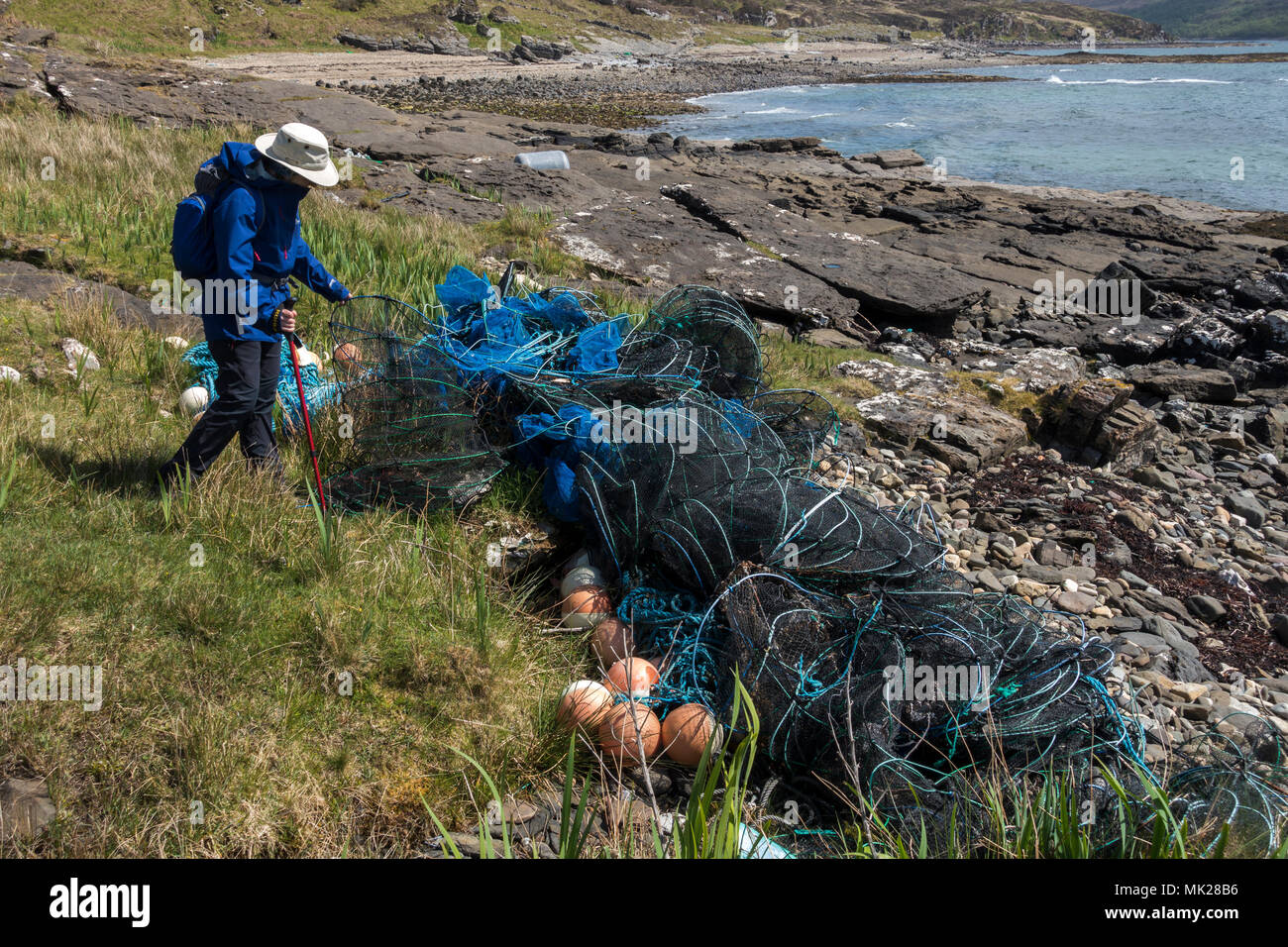 Walker examinant les plastiques et les engins de pêche en nylon sur la plage écossais, Isle of Skye, Scotland, UK Banque D'Images