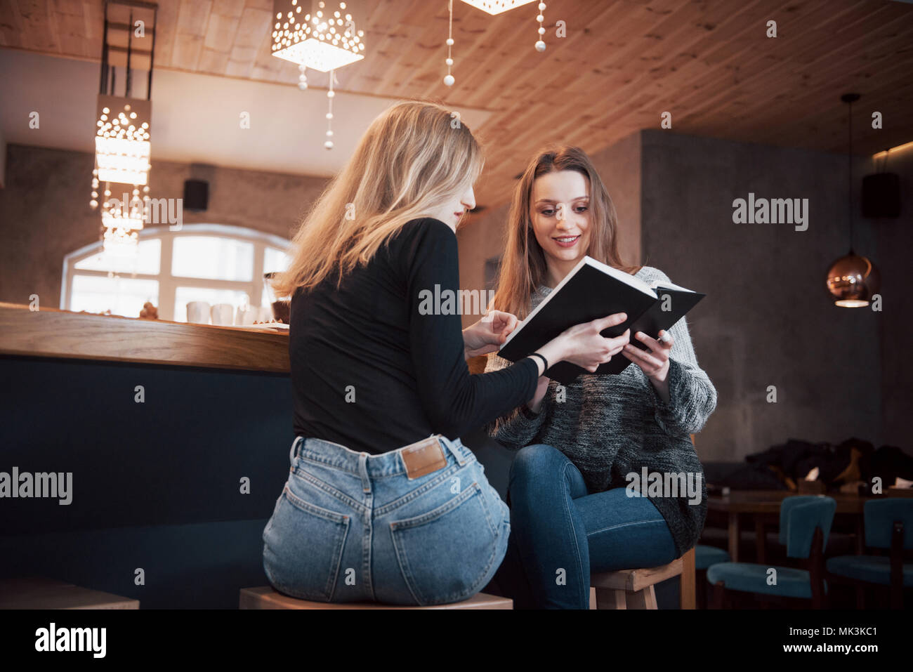 Deux jeunes femmes assises au café à boire du café et profiter de bons livres. Les étudiants sur la pause-café. L'éducation, concept de vie Banque D'Images