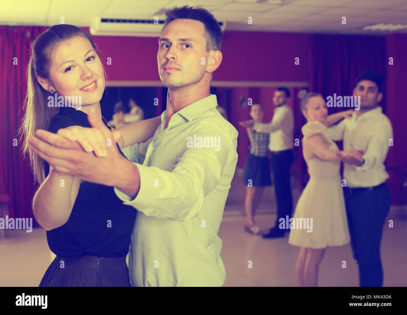 Smiling couples de danseurs appréciant foxtrot dans un studio de danse Banque D'Images