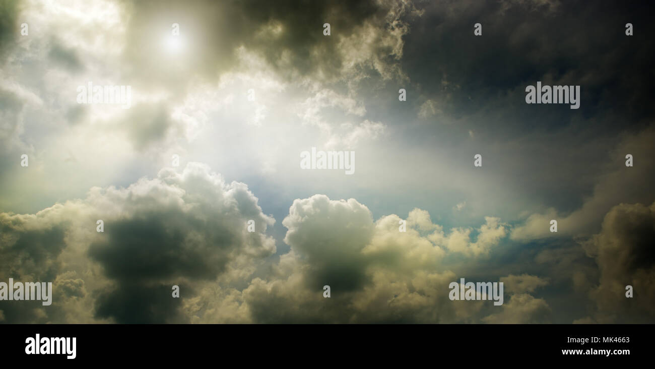Nuageux ciel sombre et le soleil derrière les nuages. Banque D'Images