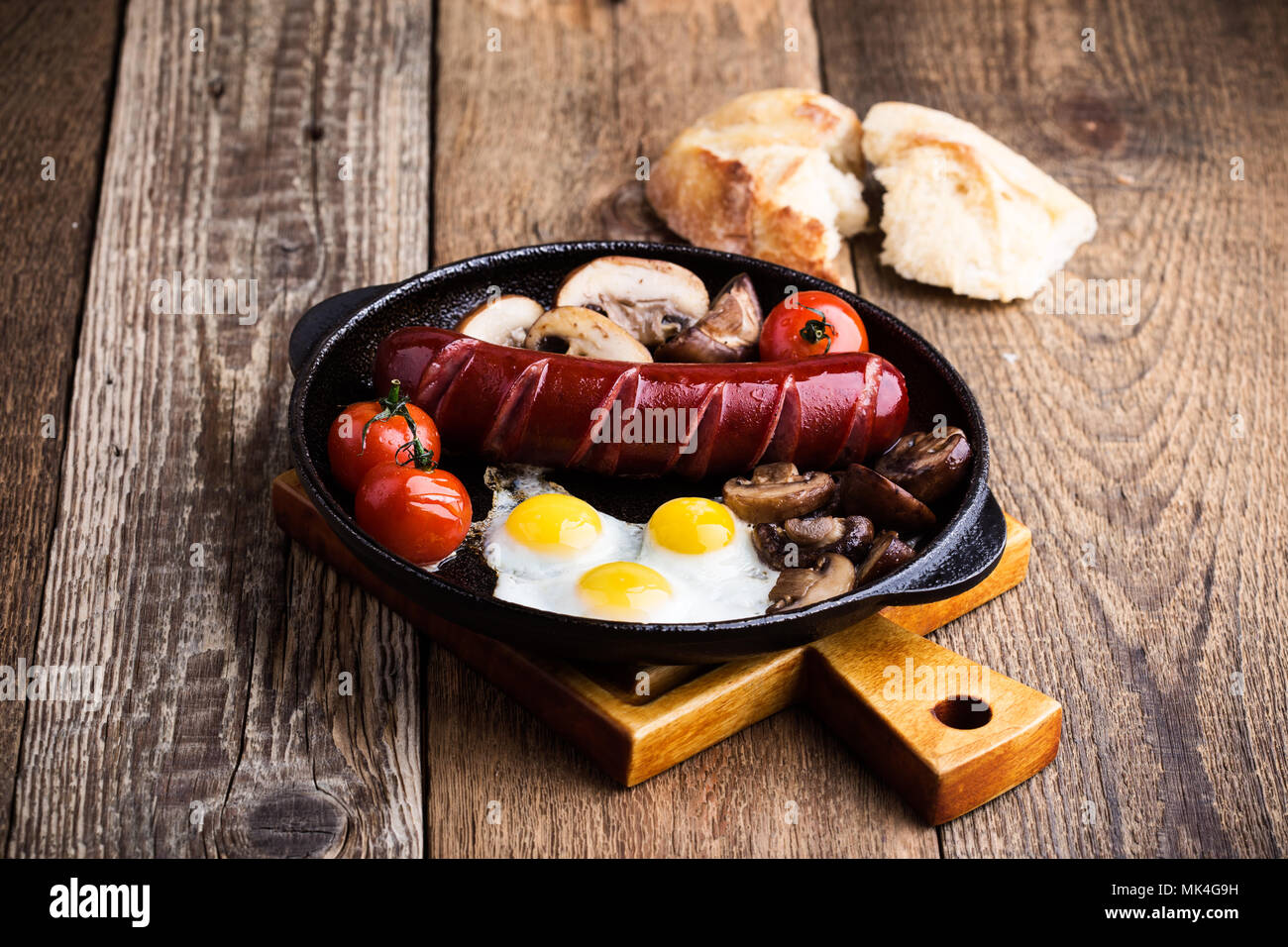 Oeufs de caille au plat, saucisses, tomates et champignons sur le poêle en fonte, petit déjeuner anglais style rustique Banque D'Images