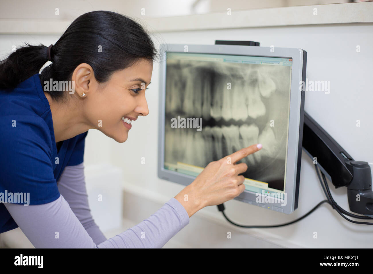 Closeup portrait of allied health professionnel de soins dentaires en bleu frotte l'examen de la radiographie dentaire sur écran d'ordinateur, bureau de dentiste isolés Banque D'Images