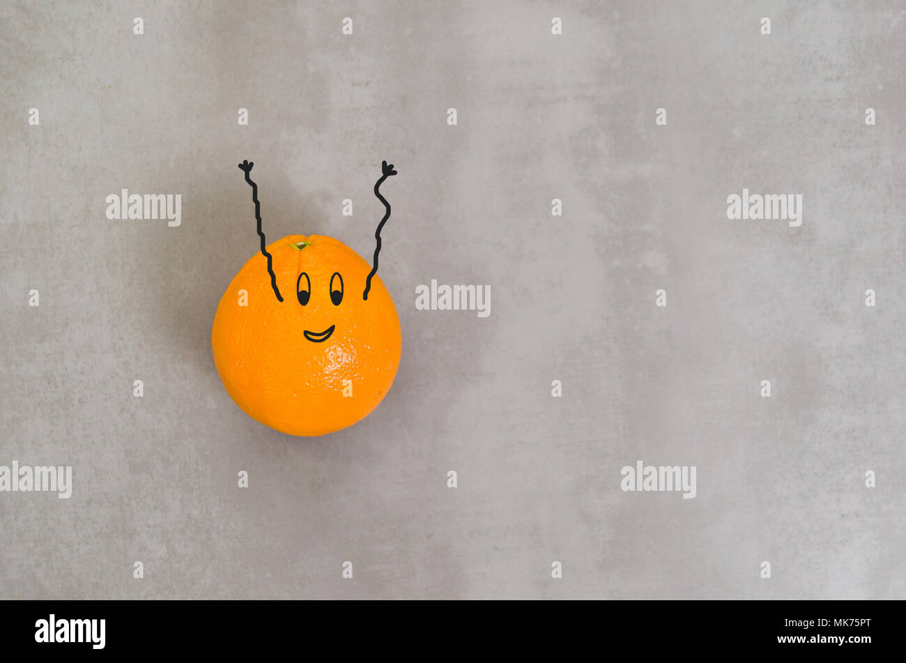 Grand concept de la saine alimentation, de l'orange avec un visage heureux et les bras vers le haut en arrière-plan gris. Banque D'Images