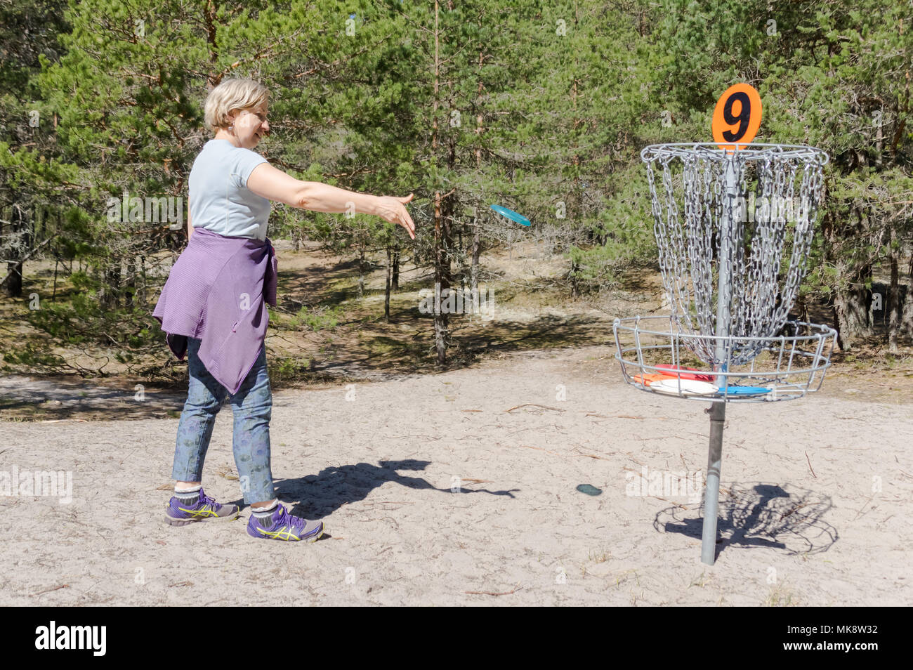 Femme jouant de disc golf sur le golf de disque Valgeranna en Estonie, jetant une battant disct au trou numéro 9 Banque D'Images