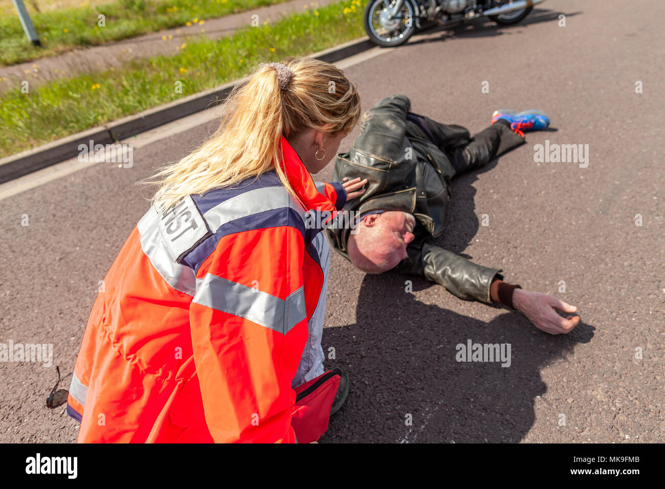 Un ambulancier allemand aide un motocycliste blessé. Rettungsdienst est le mot allemand pour les services d'ambulance. Banque D'Images