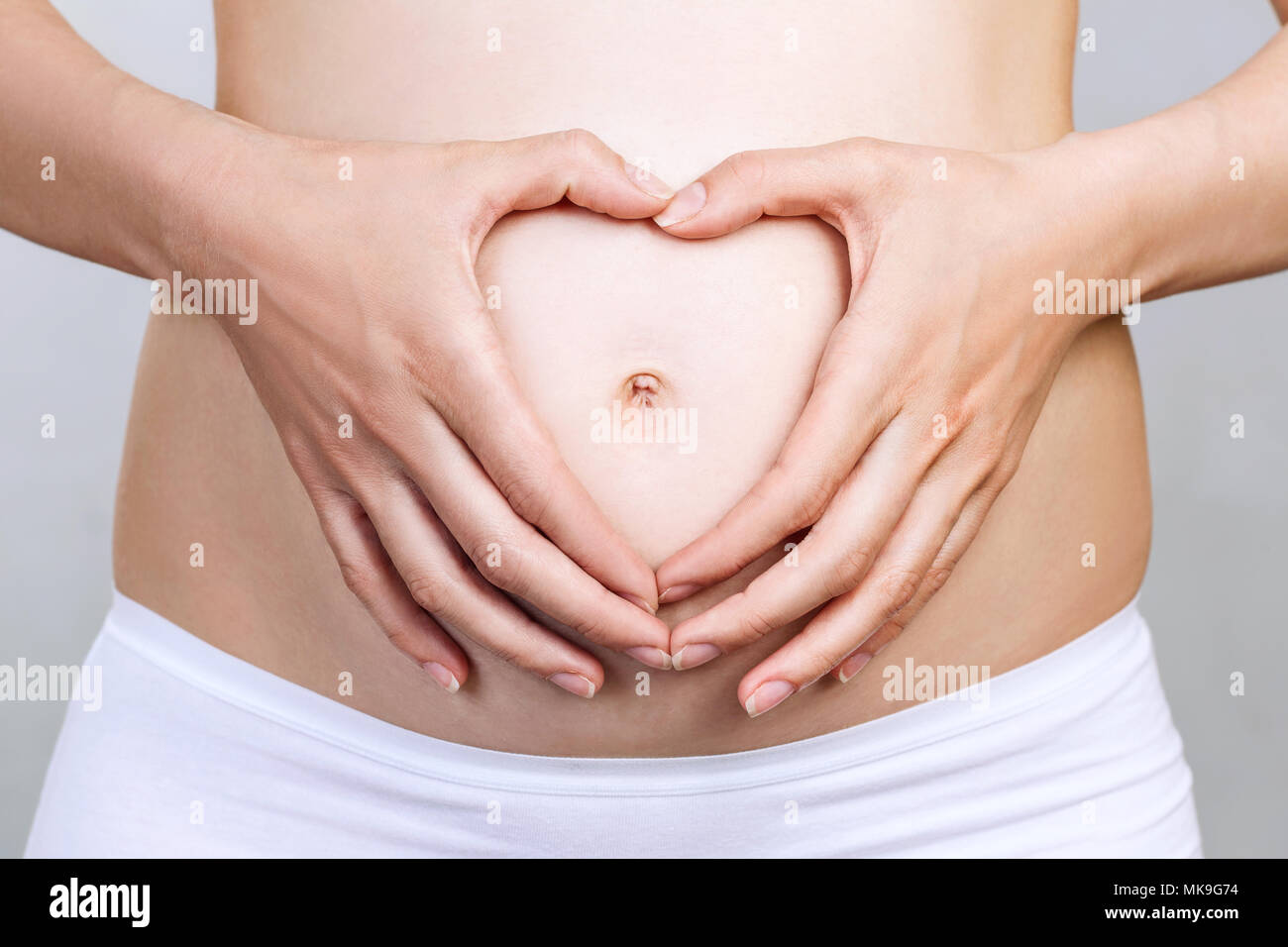Pregnant woman holding ses mains en forme de coeur sur le ventre. Banque D'Images
