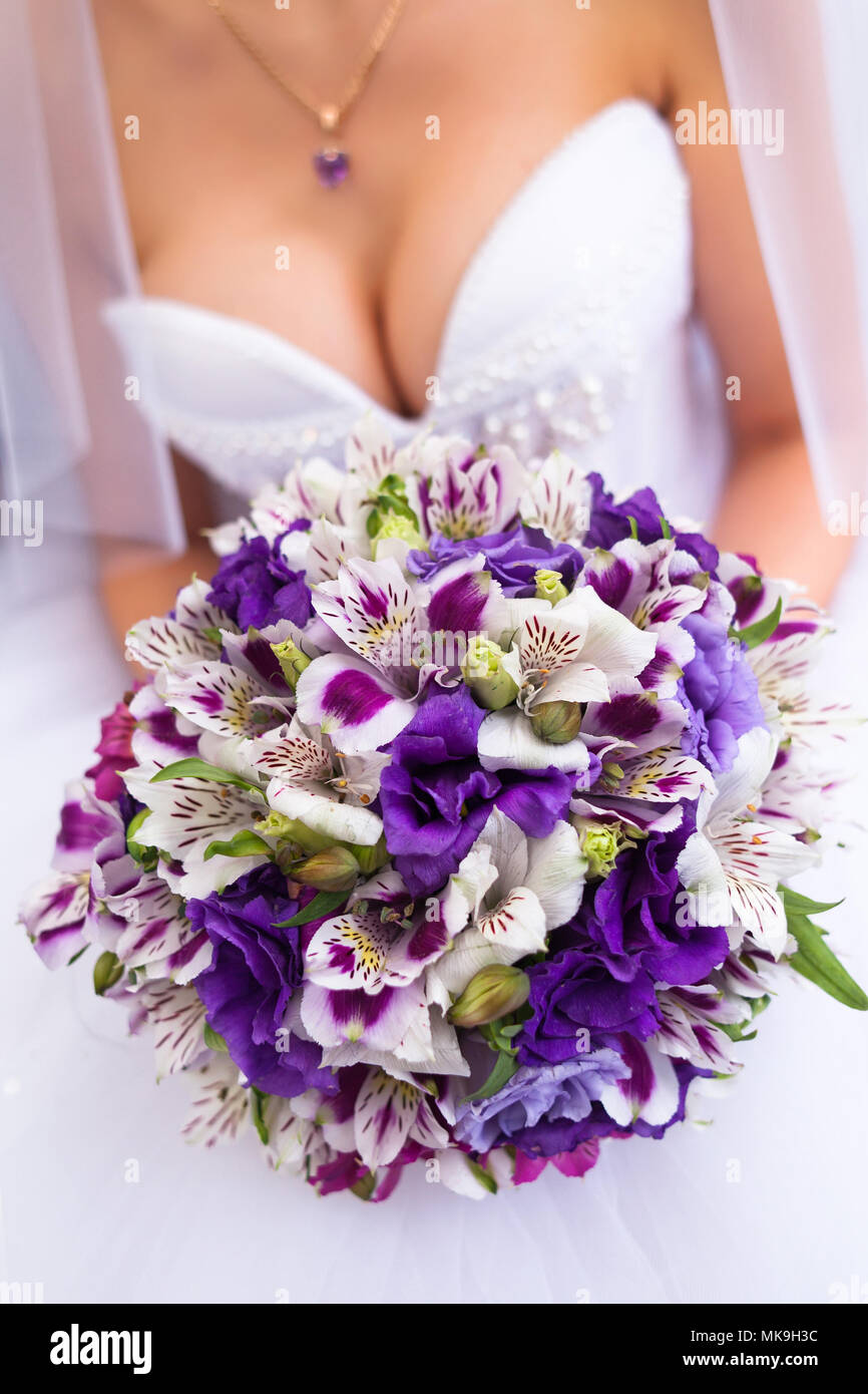 Mariee dans une robe de mariee blanche holding bouquet violet. Belle suite nuptiale robe decollete Photo Stock Alamy