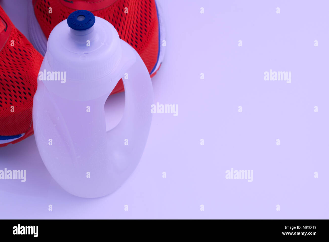 La formation en cours d'exécution orange vif, les chaussures à la bouteille d'eau sport isolé sur un fond blanc. Courir, courir, l'exercice concept Banque D'Images