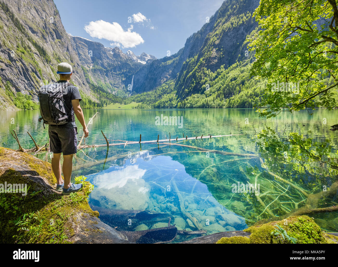 Jeune randonneur debout au bord du pittoresque lac Obersee, sur une belle journée ensoleillée avec ciel bleu en été, Berchtesgadener Land, Bavière, Allemagne Banque D'Images