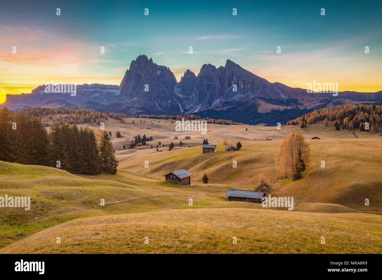 Chalets de montagne traditionnels à un panorama de l'Alpe di Siusi célèbre Langkofel avec des pics de montagne dans l'arrière-plan au lever du soleil, Dolomites, Tyrol du Sud, Italie Banque D'Images