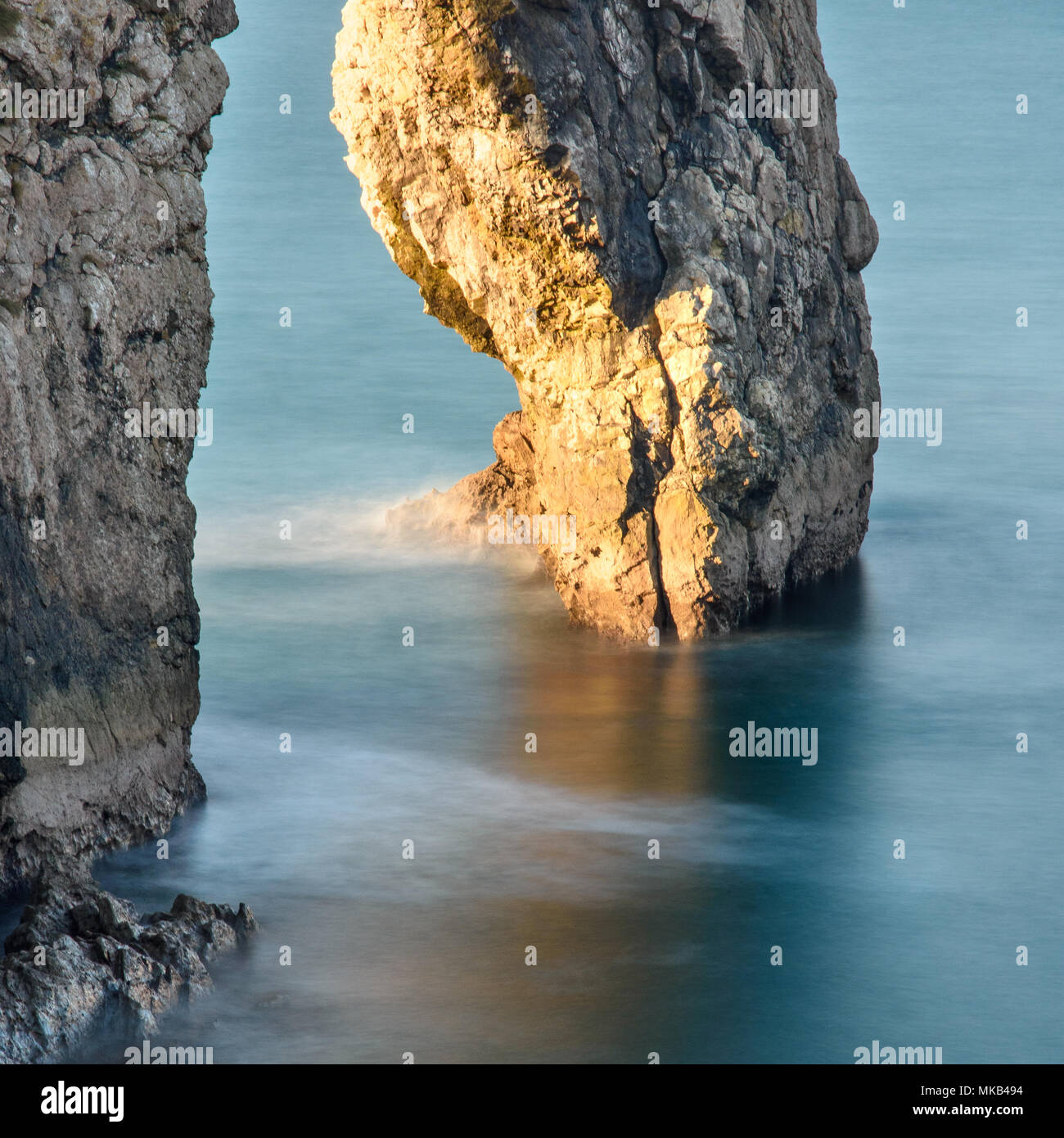 Tôt le matin, la lumière brille à travers le passage de pierre calcaire naturelle Durdle Door sur la côte jurassique. Banque D'Images