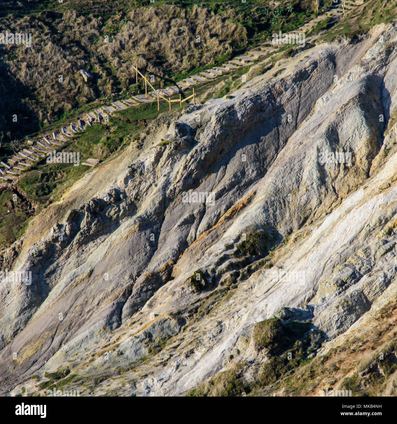 Une bande de roches argile faible forme un glissement entre les falaises de calcaire plus dur à Durdle Door, un honeypot touristique populaire sur l'emplacement du Dorset Co Jurassique Banque D'Images
