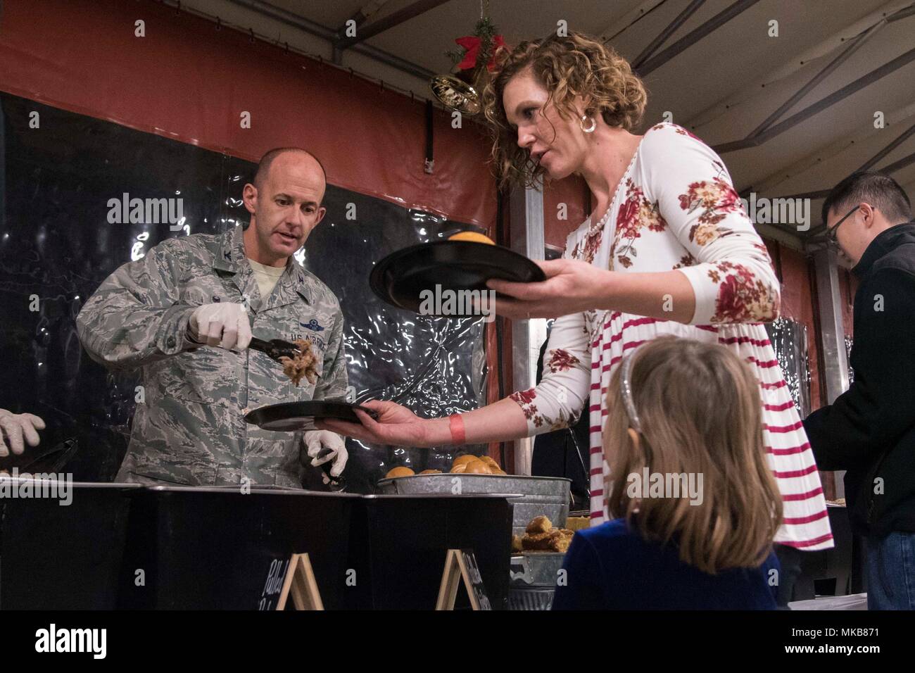 Le colonel E. John Teichert, Joint Base Andrews et 11e commandant de l'Escadre, sert de la nourriture à une famille de militaires au cours de la 11e cérémonie des lumières des fêtes à JBA, Md., le 30 novembre 2017. L'arbre éclairage fourni la base avec l'occasion de célébrer les fêtes et à prendre un moment pour rappeler les membres de service déployées pendant les vacances. (U.S. Air Force photo par un membre de la 1re classe Valentina Lopez) Banque D'Images