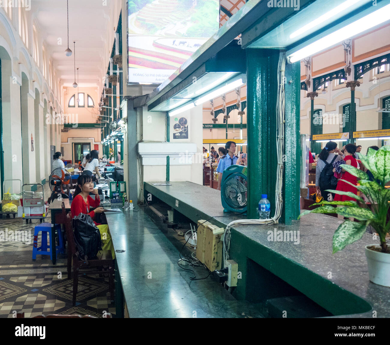 Une Vietnamienne assis au comptoir pour les clients d'attente dans le bureau de poste central, Ho Chi Minh Ville, au Vietnam. Banque D'Images