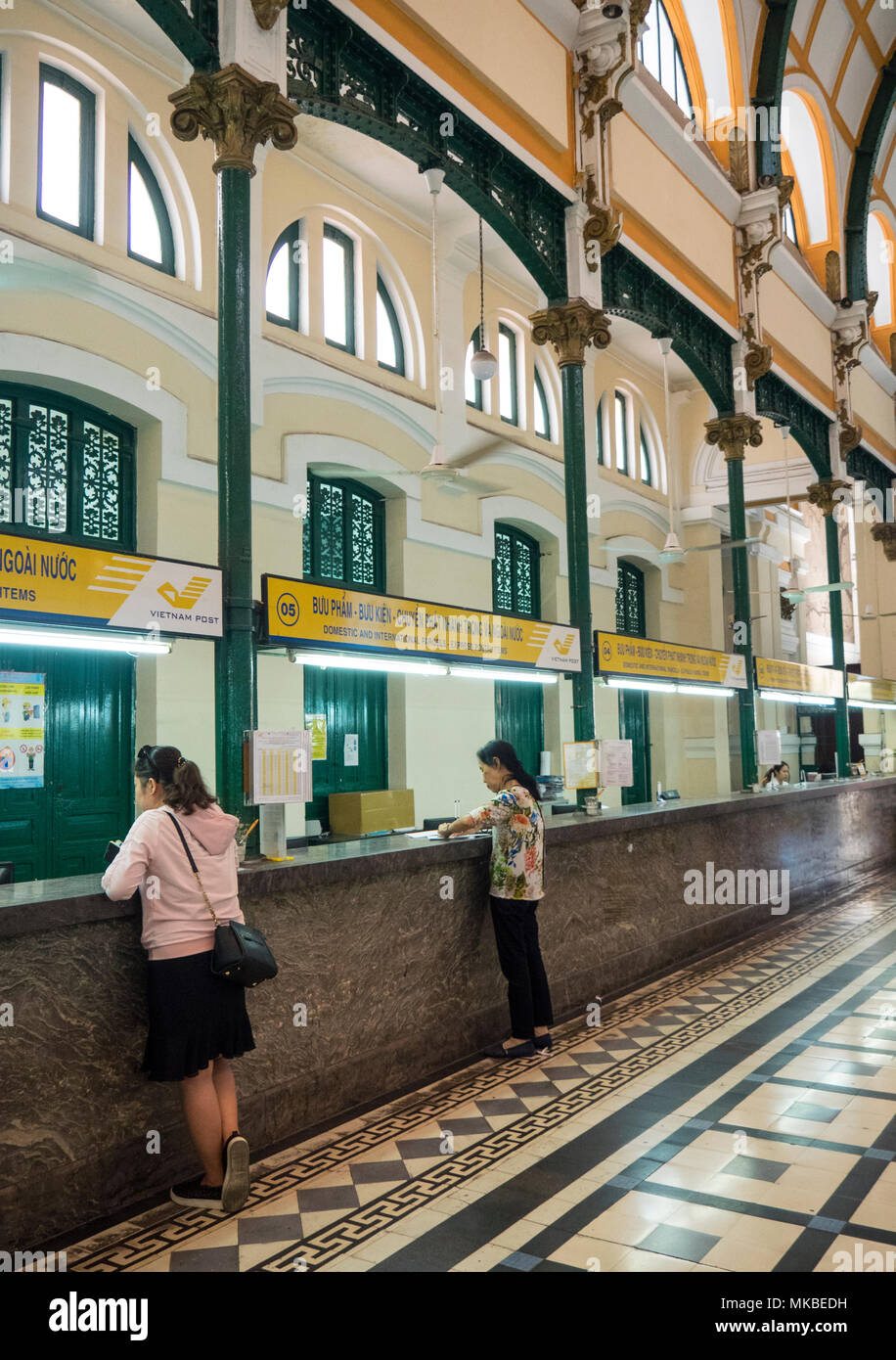 Deux femmes vietnamiennes au guichet de la Poste Centrale de Saigon à Ho Chi Minh City, Vietnam. Banque D'Images