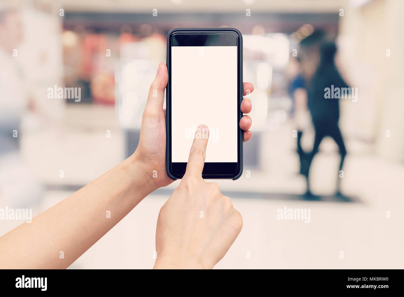 Femme tenant à la main et à l'aide de téléphone avec l'arrière-plan flou dans centre commercial. Banque D'Images