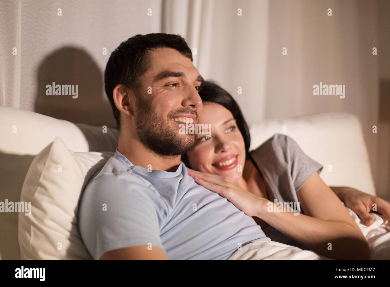 Couple heureux de regarder la télévision au lit la nuit à la maison Banque D'Images