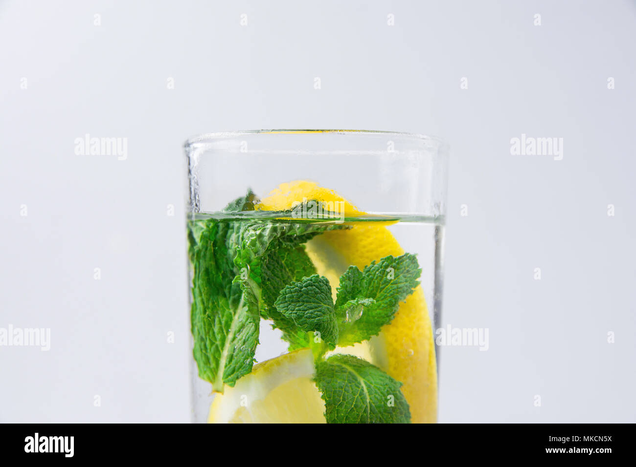 Frais Frais infusé avec de l'eau Detox bio Menthe citrons mûrs tranchés dans grand verre. Arrière-plan blanc. Rafraîchissement d'été Detox boisson saine. Savs copie Banque D'Images