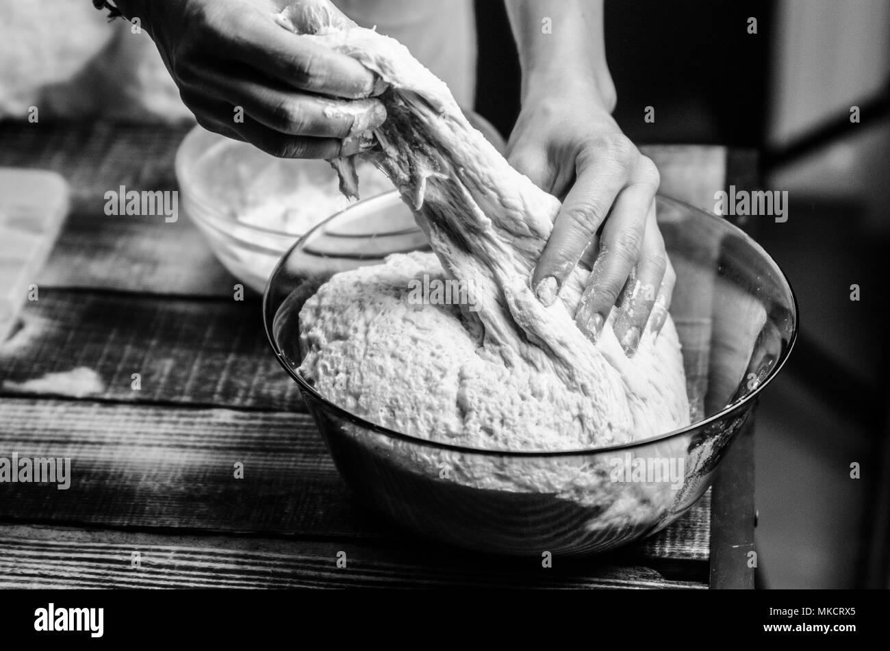 Pâte ancrés sur la planche en bois, traditionnel bretzel préparation, baker fait de pâte à pain dans la boulangerie. mains jouées avec de la farine et de la pâte. Banque D'Images