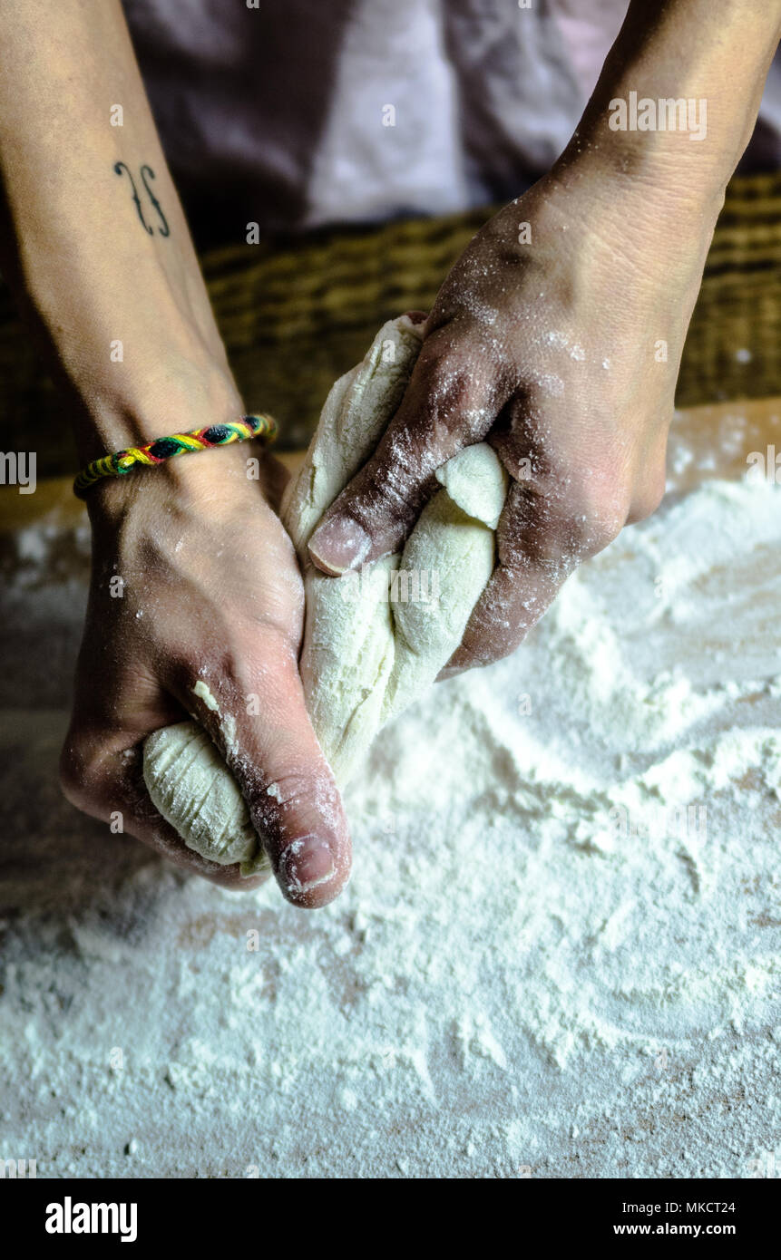 Pâte ancrés sur la planche en bois, traditionnel bretzel préparation, baker fait de pâte à pain dans la boulangerie. mains jouées avec de la farine et de la pâte. Banque D'Images