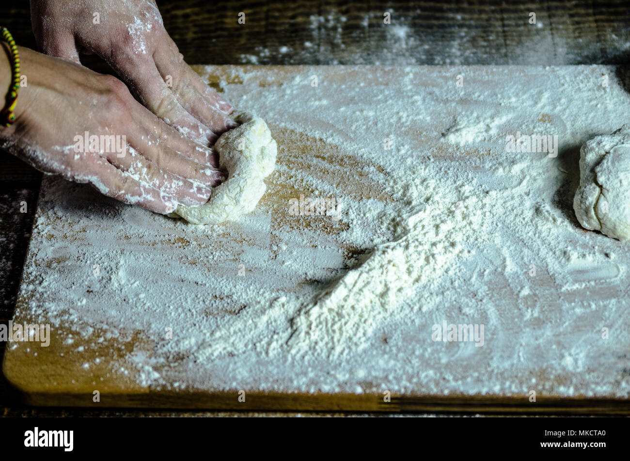 Pâte ancrés sur la planche en bois, traditionnel bretzel préparation, baker fait de pâte à pain dans la boulangerie. mains jouées avec de la farine et de la pâte. Banque D'Images