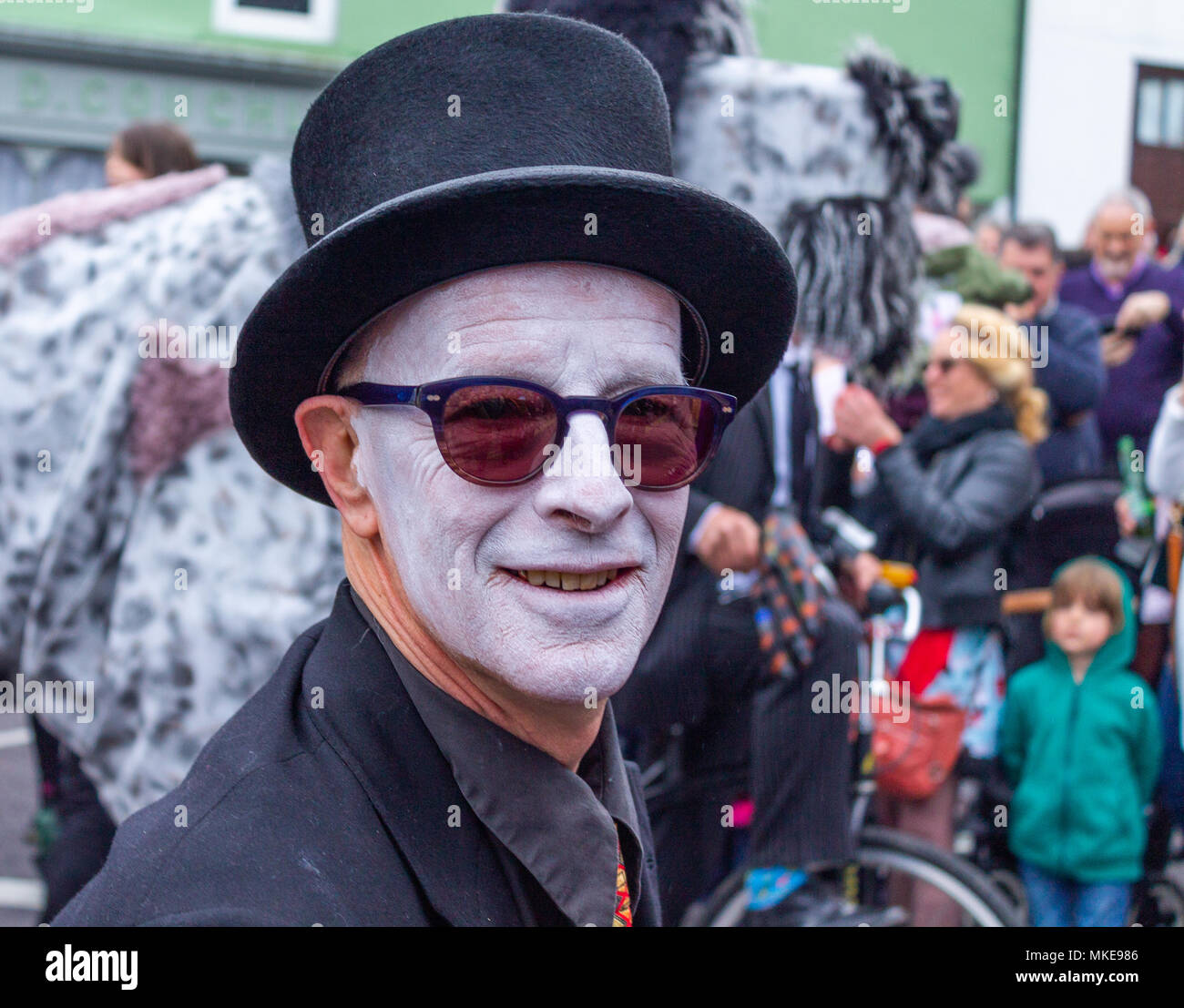 Homme avec maquillage visage de tout blanc avec des lunettes de soleil et costume noir prenant part à un festival de jazz street procession et parti à Ballydehob, Irlande Banque D'Images