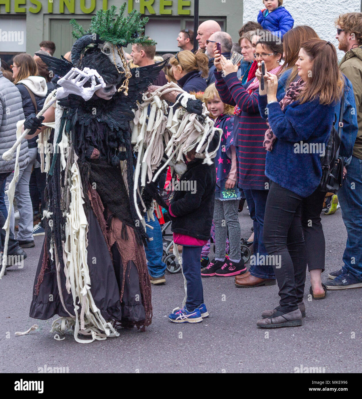 Habillés de couleurs vives street performer dans le cadre d'un festival de jazz procession habillé en sorcière dansant dans la rue de Ballydehob, Irlande Banque D'Images