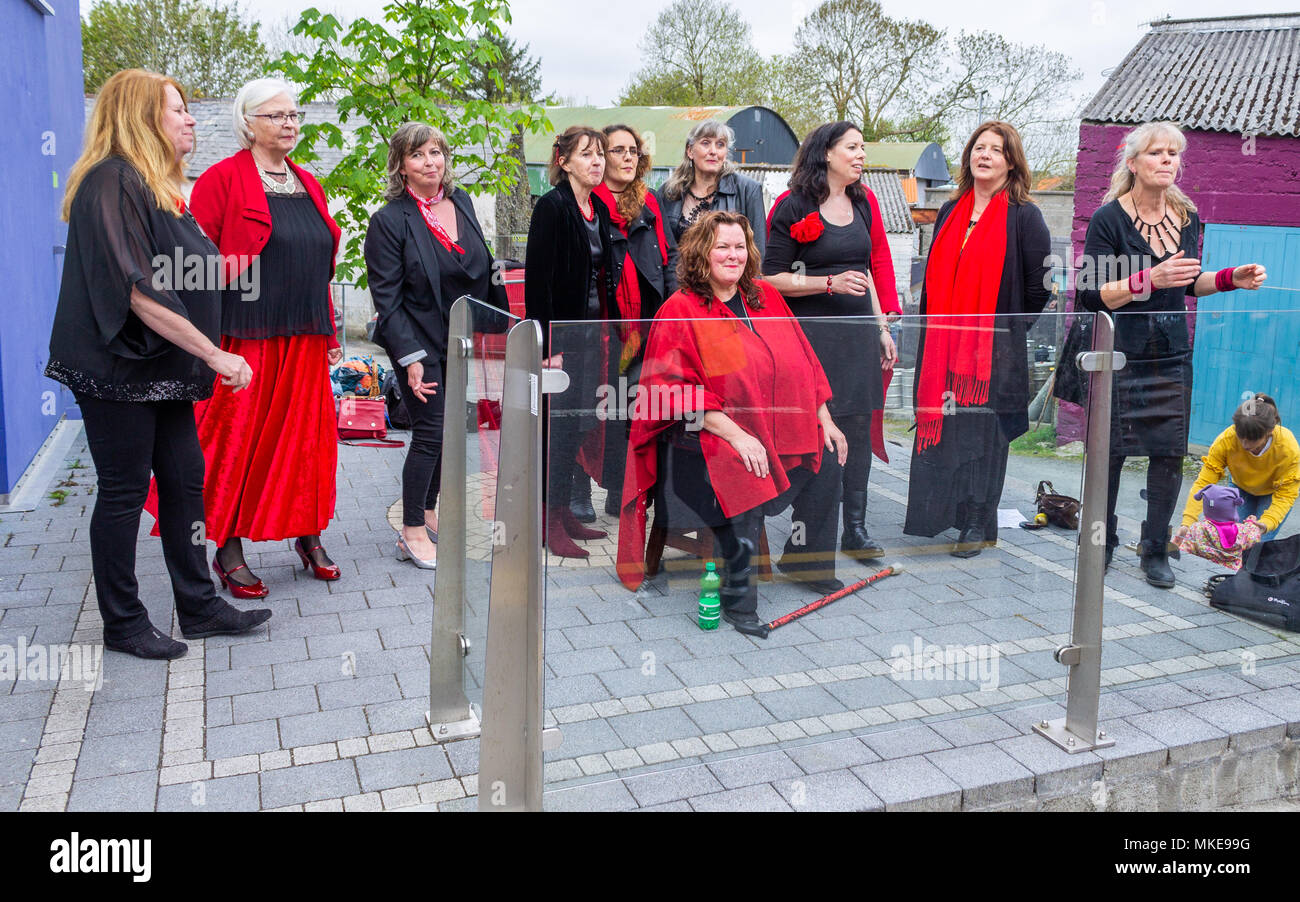 L'ensemble chœur de femmes d'effectuer à l'extérieur dans un festival de musique annuel de jazz à Ballydehob, Irlande. Les femmes sont habillées en costume rouge et noir. Banque D'Images