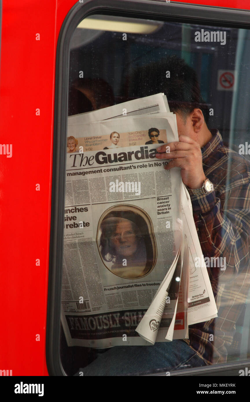 Libre d'hommes de banlieue bus lire le journal The Guardian sur un bus et faire une news rattraper Banque D'Images