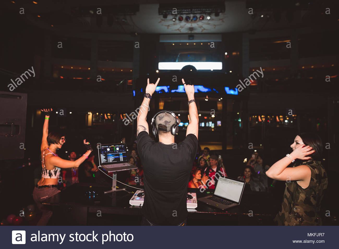 DJ enthousiaste sur scène désignant foule in nightclub Banque D'Images