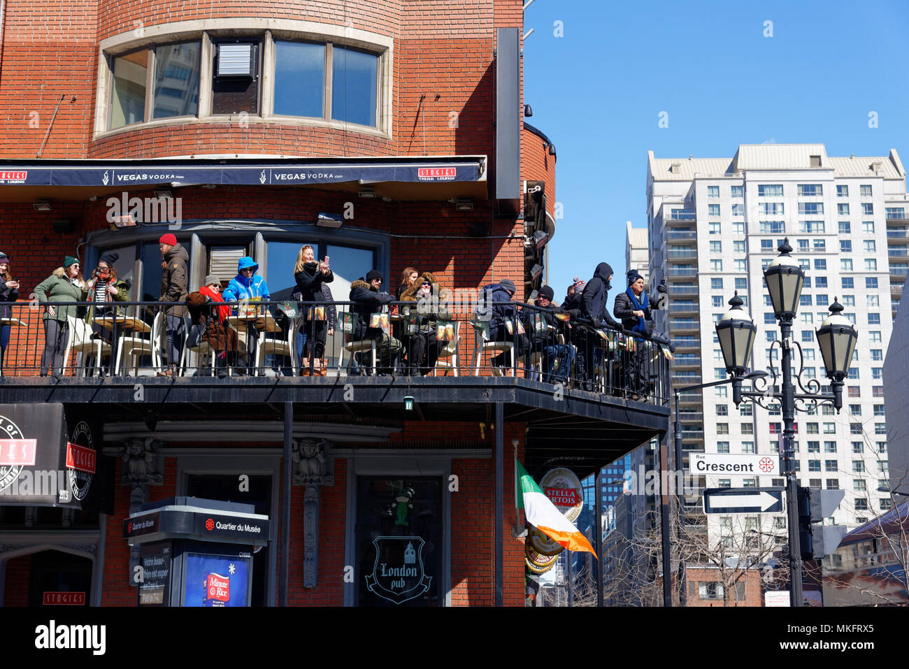 Les gens sur la terrasse d'un pub à regarder la parade de la St Patrick, à l'angle de Ste Catherine et le croissant Banque D'Images