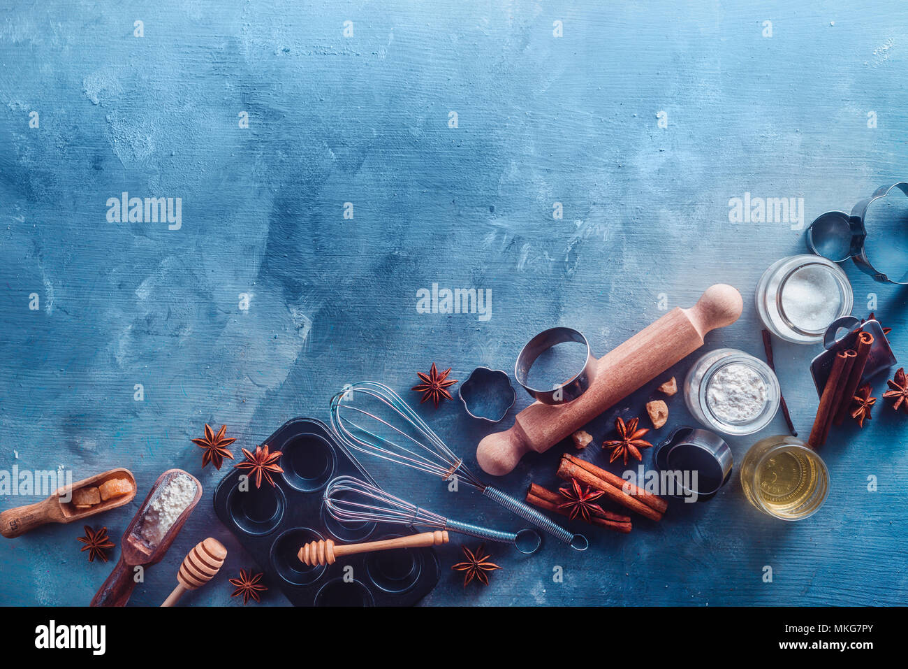 Ce concept de pâtisserie avec outils de cuisson et les ingrédients sur un fond moderne en béton avec copie espace. Boules en bois, fouets, emporte-pièce, muffin étain, le sucre, la farine et la cannelle à partir de ci-dessus. Banque D'Images
