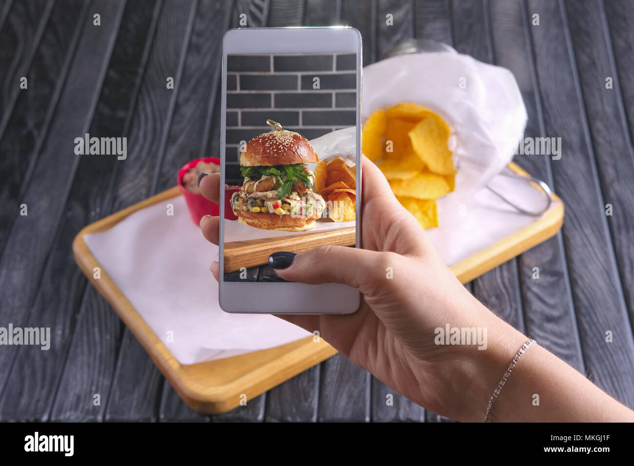 Faire de photo avec téléphone portable de bacon burger avec des nachos sur plaque de bois. Blogging alimentaire. Banque D'Images