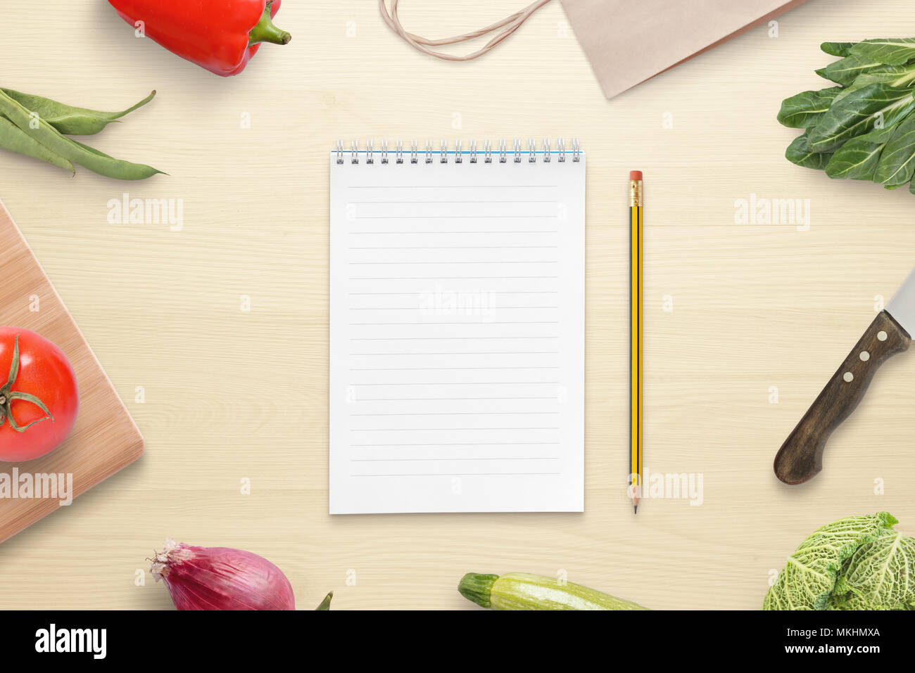 Papier et crayon pour la recette ou la liste des ingrédients. Table de cuisine avec couteau, cuting, sac de marché et les légumes. Banque D'Images