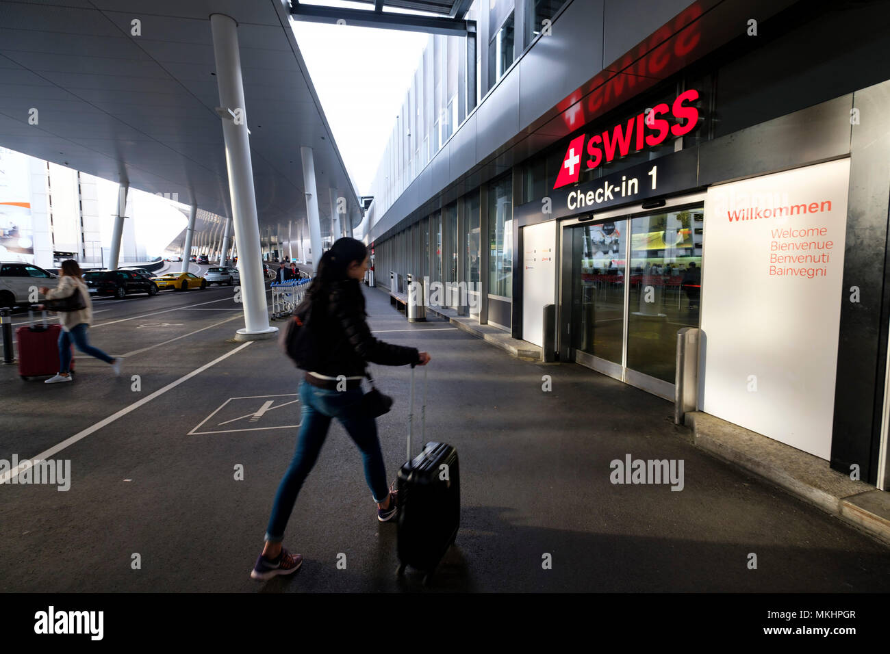 Voyageur femelle entrant dans le l'aéroport de Zurich avec un rolling suitcase, Zurich, Switzerland, Europe Banque D'Images