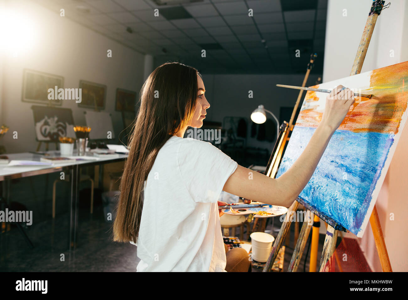 Jeune femme peintre amateur photo dessin sur toile avec des peintures à l'huile dans son atelier Banque D'Images