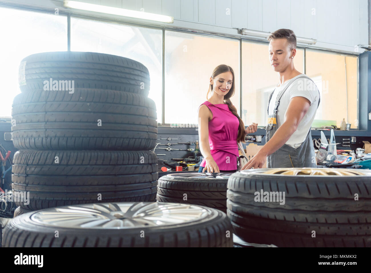 Beau mécanicien auto aider un client à choisir parmi différents pneumatiques Banque D'Images